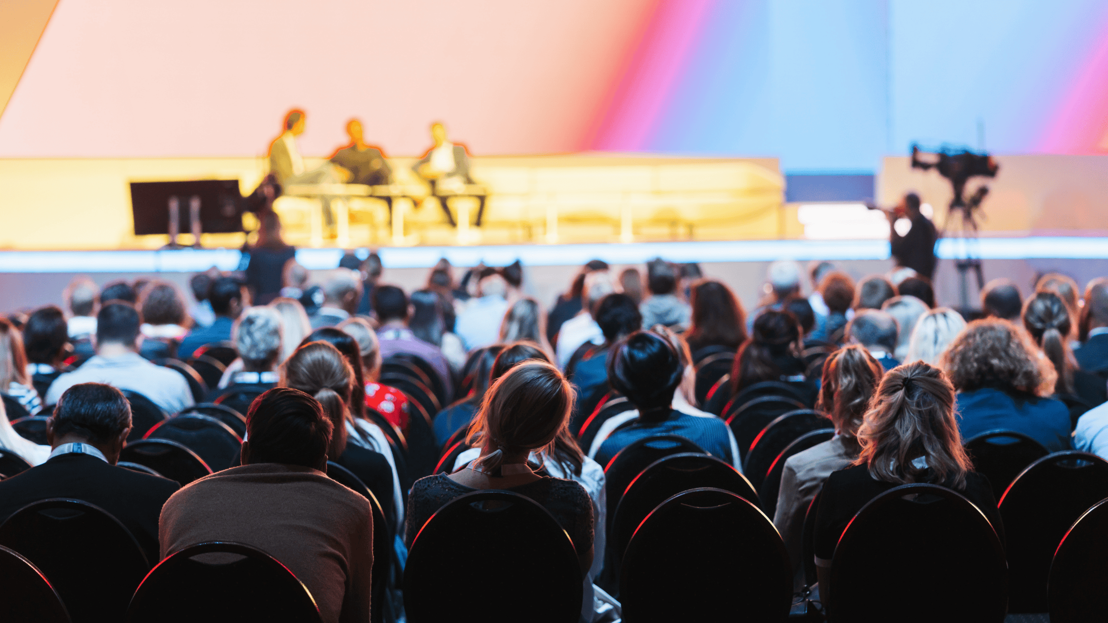 A conference panel discussion on stage with an attentive audience listening and engaging in the session.